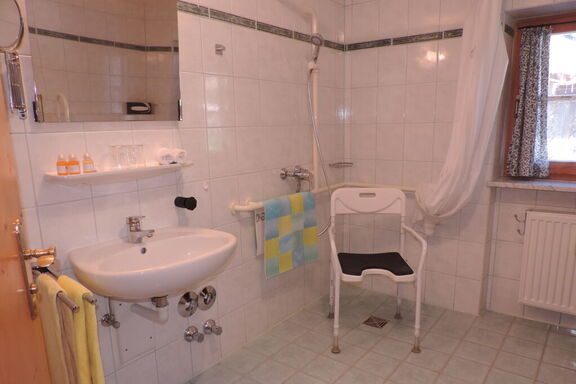 ebenerdige Dusche mit Duschstuhl, unterfahrbares Waschbecken mit Kippspiegel